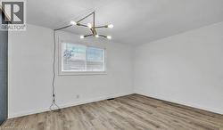 Empty room with light wood-style flooring and a chandelier -