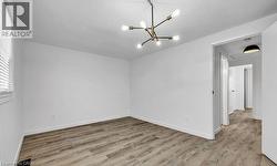 Empty room featuring light wood-type flooring and a chandelier -