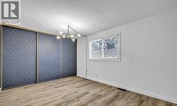 Spare room with an accent wall, light wood-type flooring, and a chandelier -