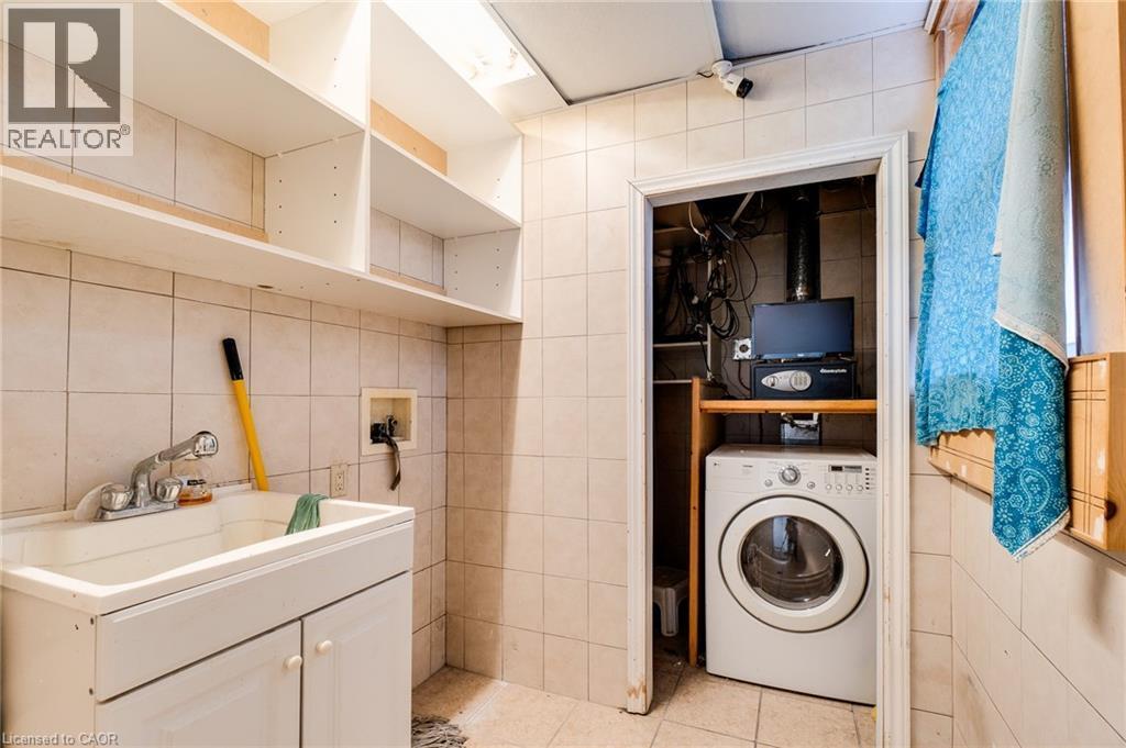 Washroom with washer / clothes dryer, tile walls, and light tile patterned floors - 18 Barton Street E Unit# A, Hamilton, ON