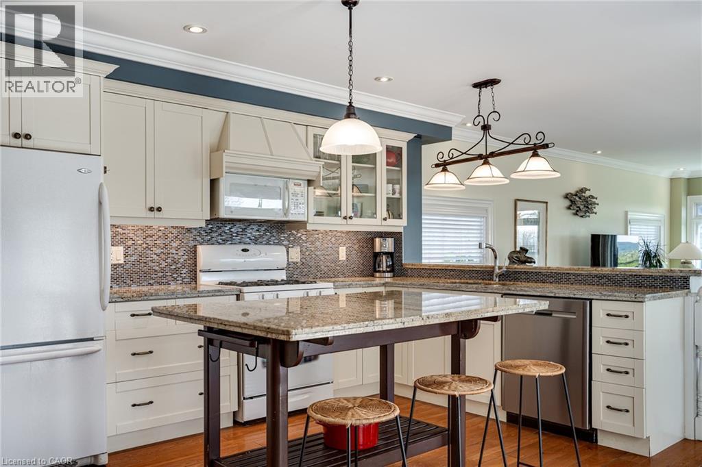 Kitchen with a kitchen breakfast bar, white appliances, pendant lighting, crown molding, and glass insert cabinets - 849 Beach Boulevard, Hamilton, ON - Indoor Photo Showing Kitchen