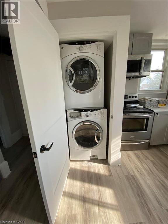 Washroom with light wood finished floors and stacked washing machine and dryer - 193 Balmoral Avenue N, Hamilton, ON - Indoor Photo Showing Laundry Room