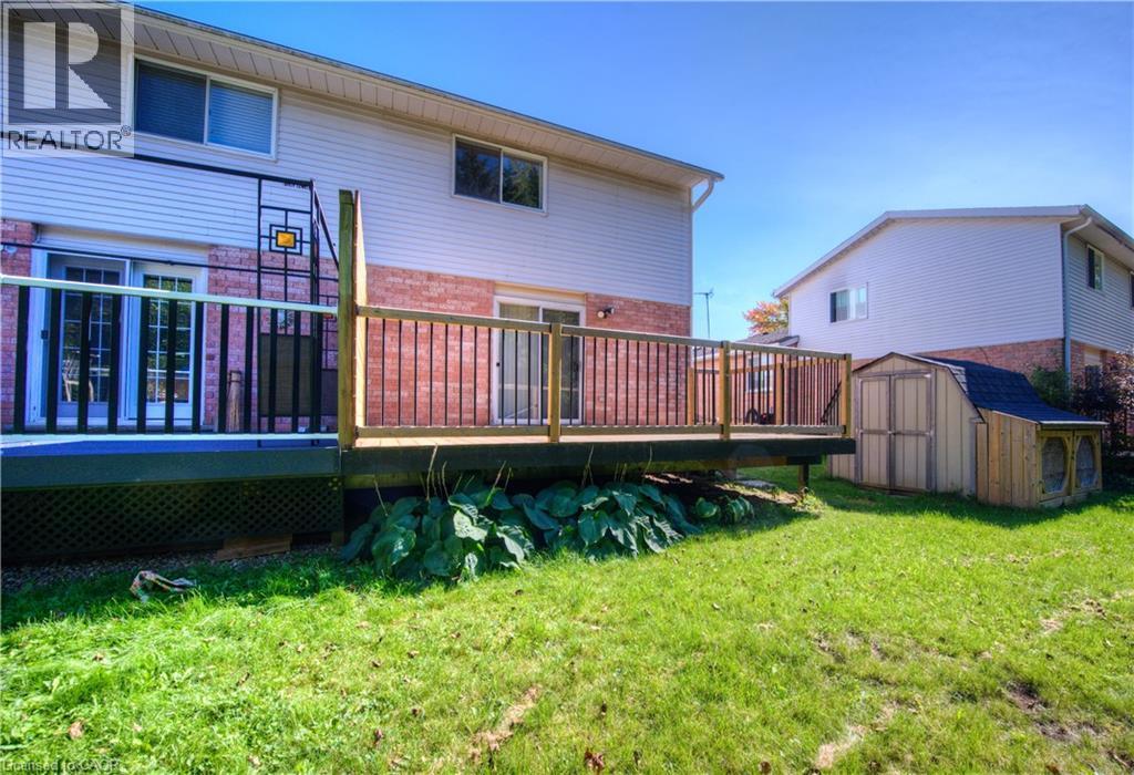 Rear view of property featuring a deck, brick siding, a storage unit, and a lawn - 236 Bankside Drive, Kitchener, ON - Outdoor With Deck Patio Veranda
