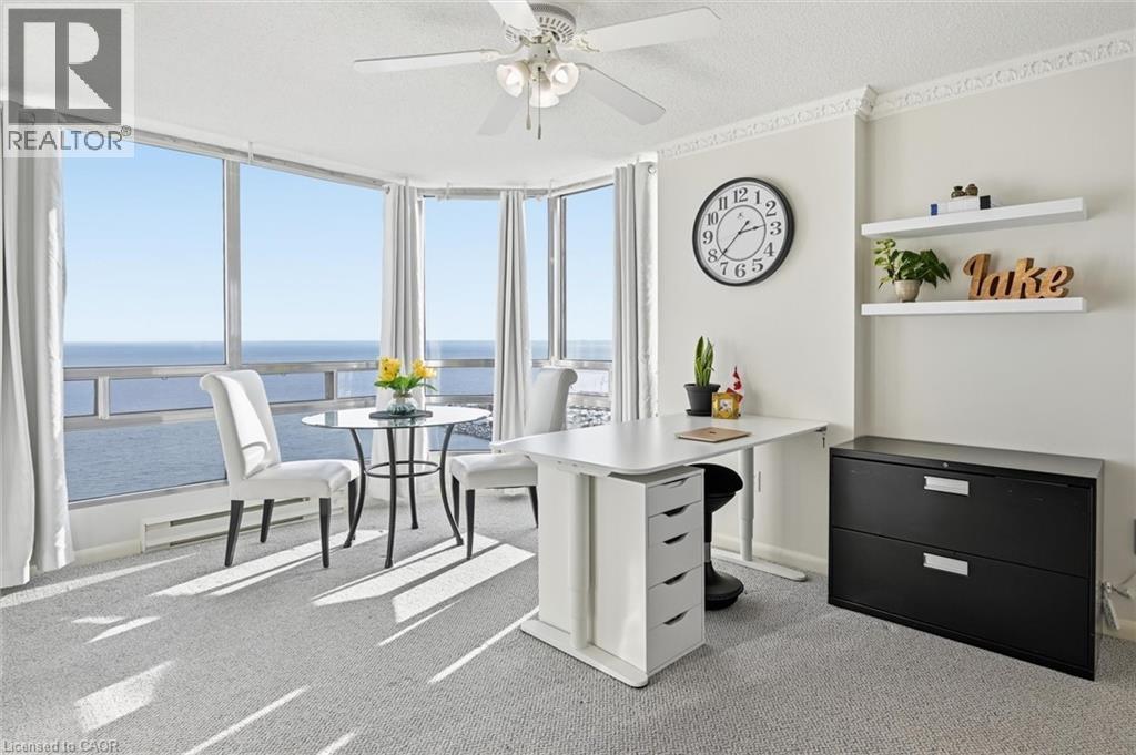 Office space featuring a water view, light carpet, a baseboard heating unit, floor to ceiling windows, and a textured ceiling - 2170 Marine Drive Unit# 1808, Oakville, ON - Indoor