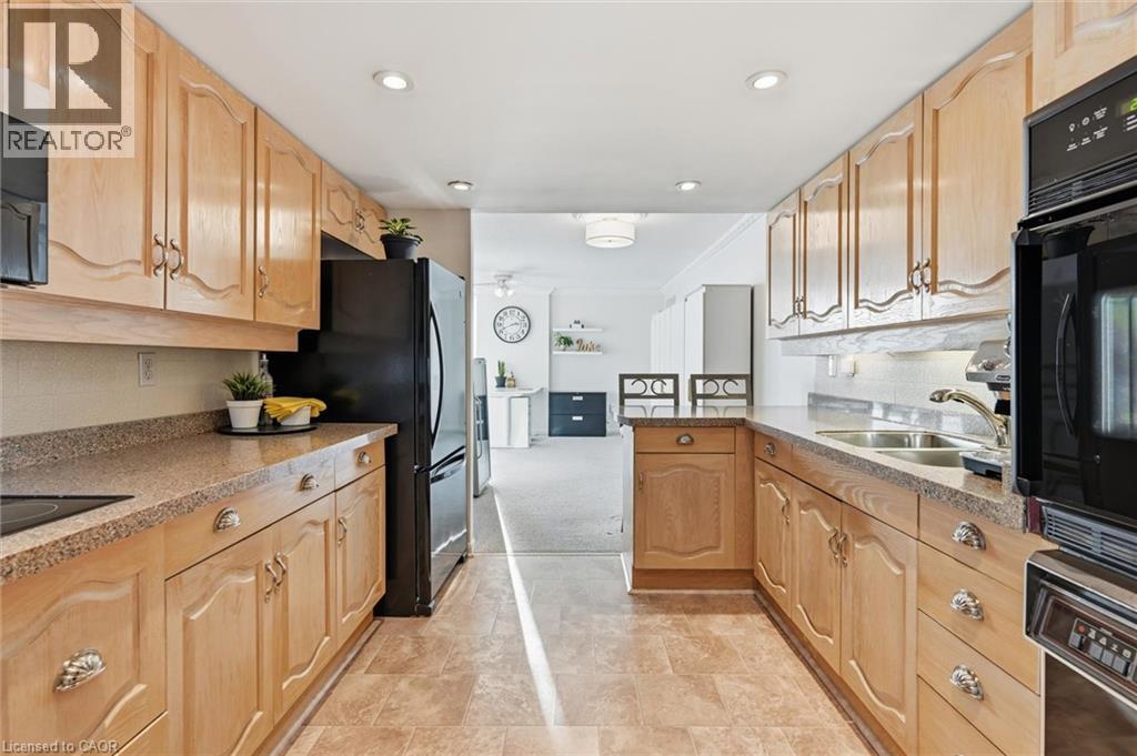 Kitchen with dark stone counters, black appliances, a peninsula, ornamental molding, and recessed lighting - 2170 Marine Drive Unit# 1808, Oakville, ON - Indoor Photo Showing Kitchen With Double Sink