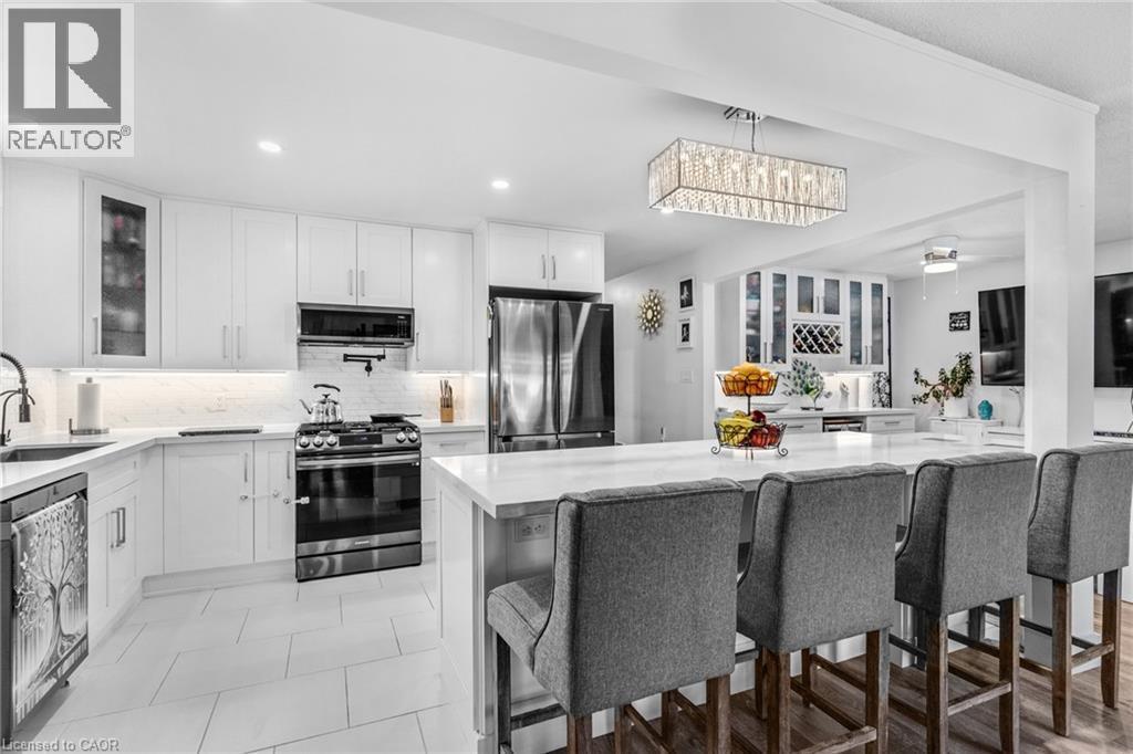 Kitchen with glass insert cabinets, appliances with stainless steel finishes, white cabinetry, light stone counters, and recessed lighting - 136 Limpert Avenue, Cambridge, ON - Indoor Photo Showing Kitchen With Upgraded Kitchen