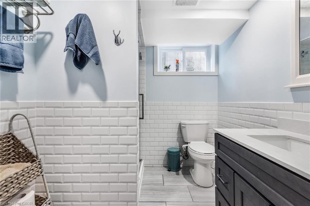 Full bath with a wainscoted wall, vanity, tile walls, and a stall shower - 136 Limpert Avenue, Cambridge, ON - Indoor Photo Showing Bathroom