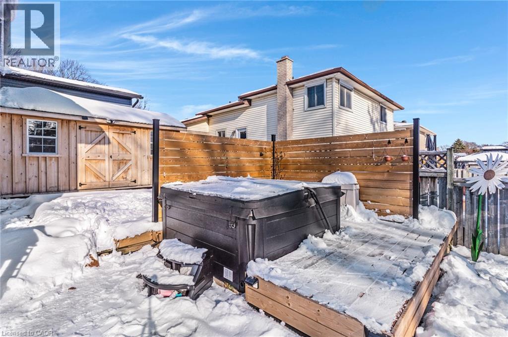 Snow covered patio featuring a hot tub, a wooden deck, and a storage unit - 136 Limpert Avenue, Cambridge, ON - Outdoor
