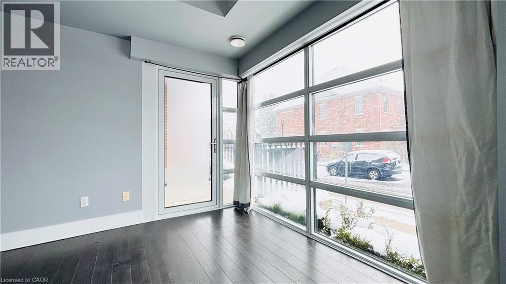 Unfurnished room featuring dark wood-style flooring and plenty of natural light - 155 St. Leger Unit# 107, Kitchener, ON - Indoor Photo Showing Other Room