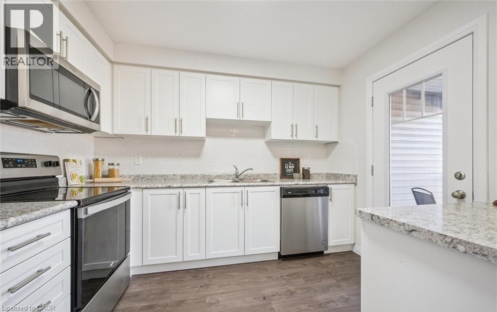 Kitchen featuring appliances with stainless steel finishes, white cabinets, and dark wood finished floors - 24 Morrison Road Unit# D9, Kitchener, ON - Indoor Photo Showing Kitchen With Double Sink With Upgraded Kitchen