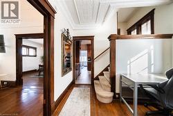 Hallway with dark wood-style floors, ornamental molding, and stairway -