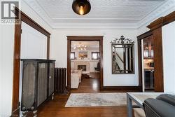 Hall featuring dark wood-style flooring, radiator heating unit, wine cooler, crown molding, and an ornate ceiling -