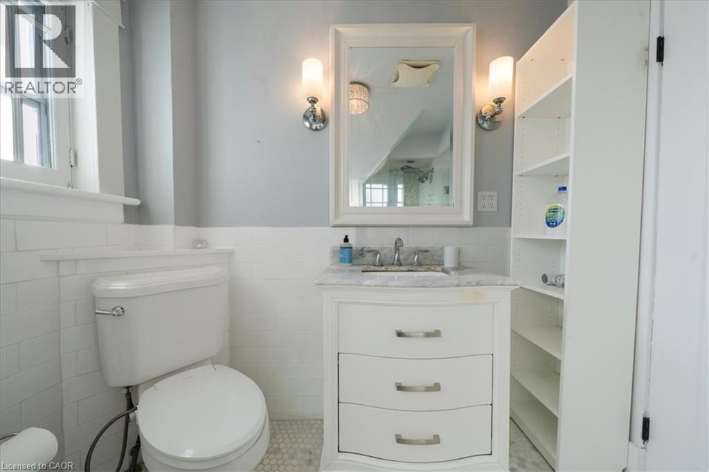 Half bath with a wainscoted wall, vanity, tile walls, healthy amount of natural light, and light tile patterned flooring - 184 Weber Street E, Kitchener, ON - Indoor Photo Showing Bathroom