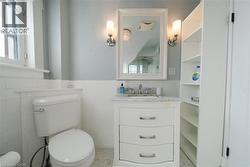 Half bath with a wainscoted wall, vanity, tile walls, healthy amount of natural light, and light tile patterned flooring -