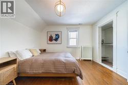 Bedroom with radiator heating unit, vaulted ceiling, wood finished floors, and a textured ceiling -