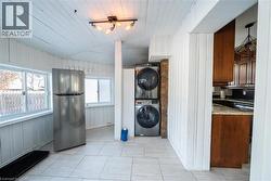 Laundry area featuring vaulted ceiling, stacked washer / dryer, wooden walls, and wood ceiling -