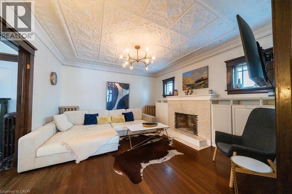 Living area with ornamental molding, an ornate ceiling, a fireplace with raised hearth, dark wood-style flooring, and a chandelier - 184 Weber Street E, Kitchener, ON - Indoor Photo Showing Living Room With Fireplace