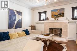 Living room with an ornate ceiling, a fireplace, wood finished floors, and crown molding -