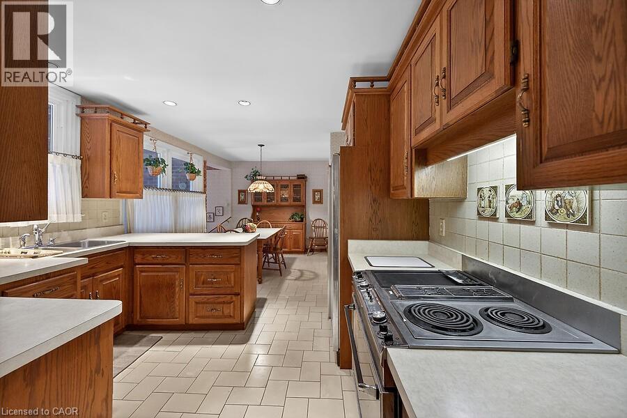 Kitchen with wood finish cabinets, a peninsula, stainless steel electric range, and light countertops - 9 Daleview Court, Hamilton, ON - Indoor Photo Showing Kitchen