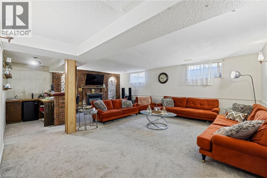 Carpeted living area featuring a textured ceiling, a brick fireplace, and brick wall - 490 Queen Victoria Drive, Hamilton, ON - Indoor