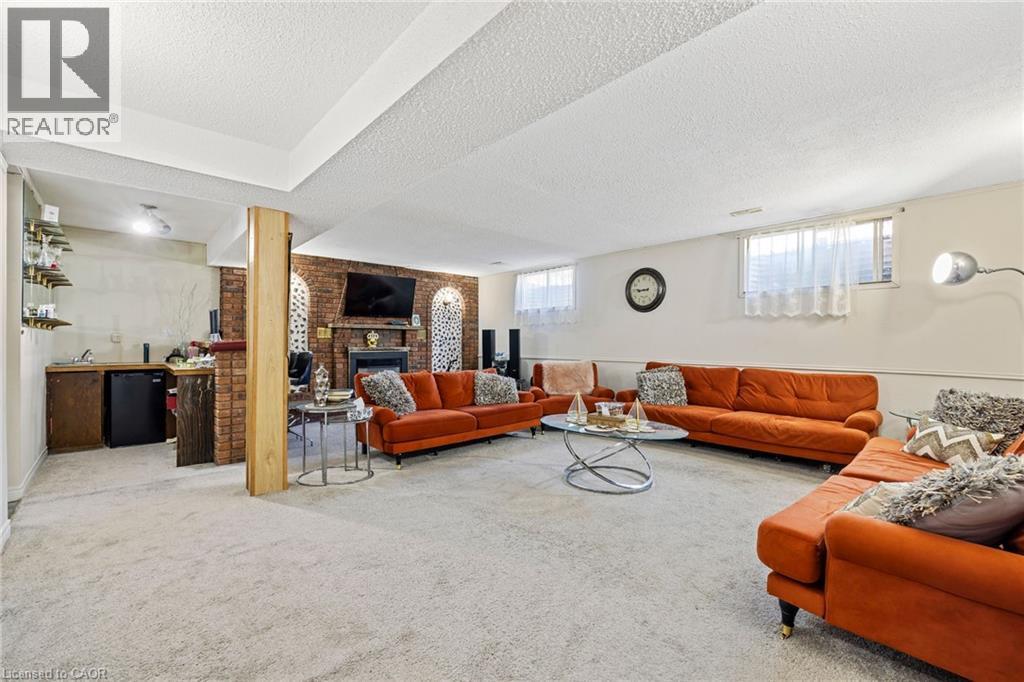 Living room featuring carpet, a fireplace, brick wall, and a textured ceiling - 490 Queen Victoria Drive, Hamilton, ON - Indoor