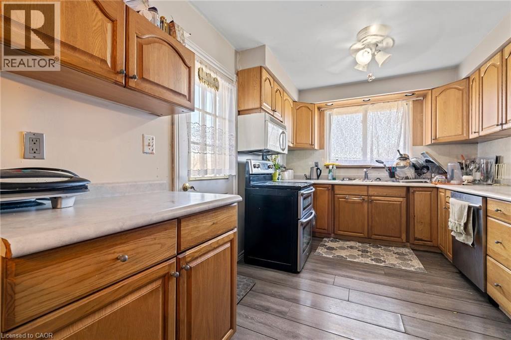 Kitchen featuring appliances with stainless steel finishes, light countertops, dark wood finished floors, and brown cabinetry - 490 Queen Victoria Drive, Hamilton, ON - Indoor Photo Showing Kitchen