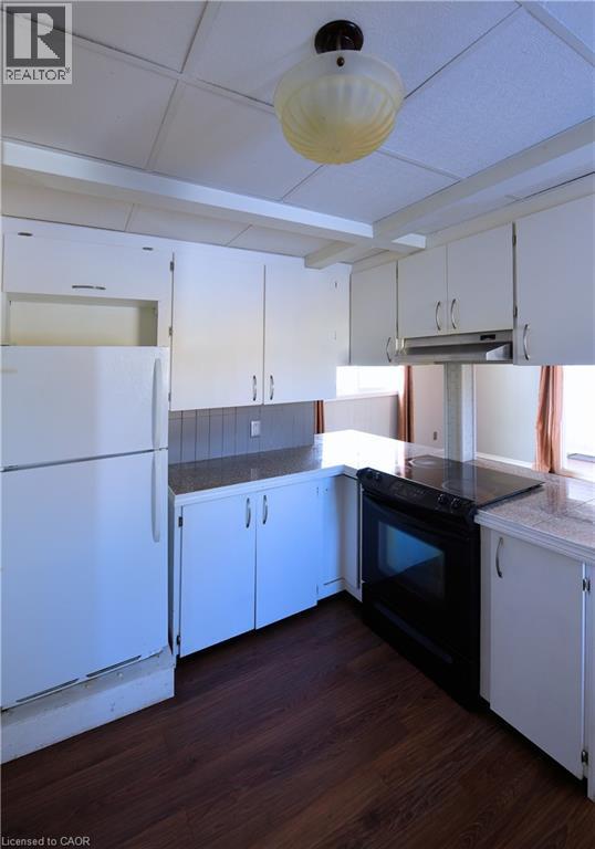 Kitchen with white cabinets, freestanding refrigerator, electric range, dark wood finished floors, and under cabinet range hood - 1448 Upper Ottawa Street, Hamilton, ON - Indoor Photo Showing Kitchen
