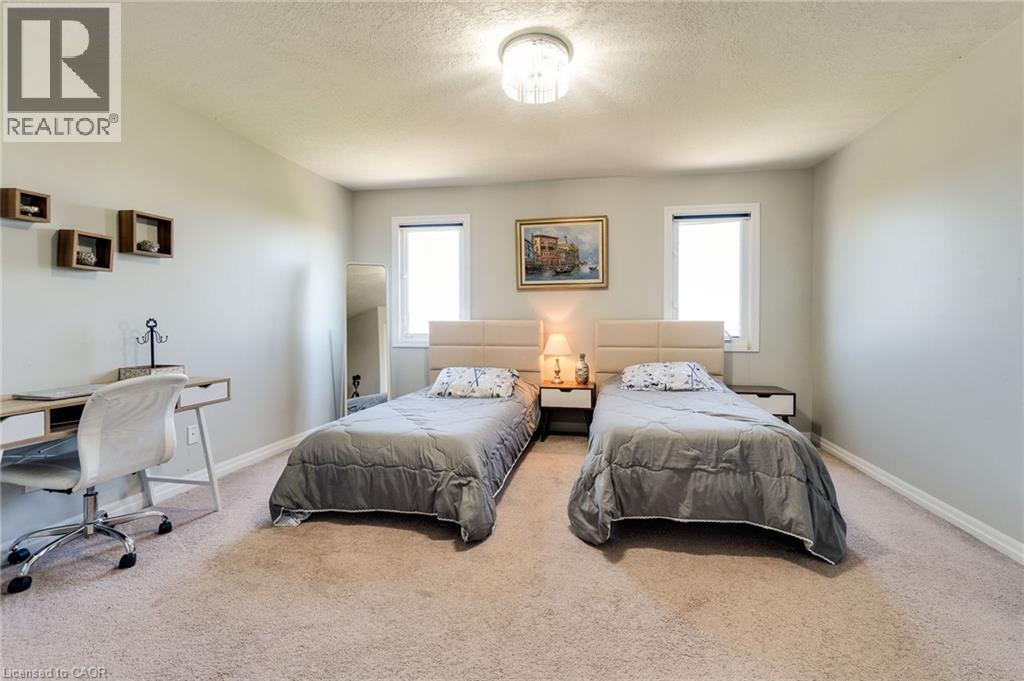 Carpeted bedroom featuring multiple windows, a desk, and a textured ceiling - 928 Dunblane Court, Kitchener, ON - Indoor Photo Showing Bedroom