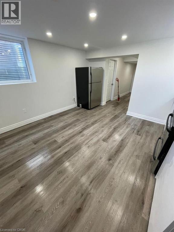 Below grade area with freestanding refrigerator, wood finished floors, and recessed lighting - 928 Dunblane Court, Kitchener, ON - Indoor