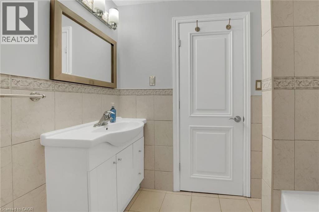 Bathroom featuring light tile patterned floors, vanity, tile walls, and wainscoting - 125 Valera Drive, Hamilton, ON - Indoor Photo Showing Bathroom