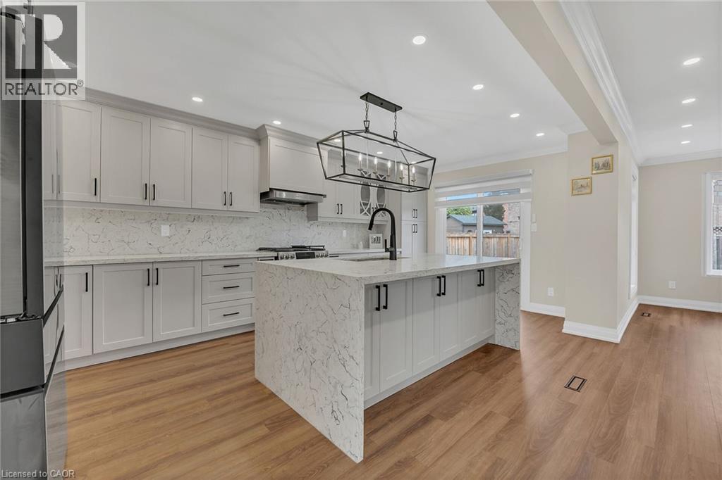 Kitchen featuring light stone countertops, recessed lighting, appliances with stainless steel finishes, backsplash, and white cabinets - 125 Valera Drive, Hamilton, ON - Indoor Photo Showing Kitchen With Upgraded Kitchen