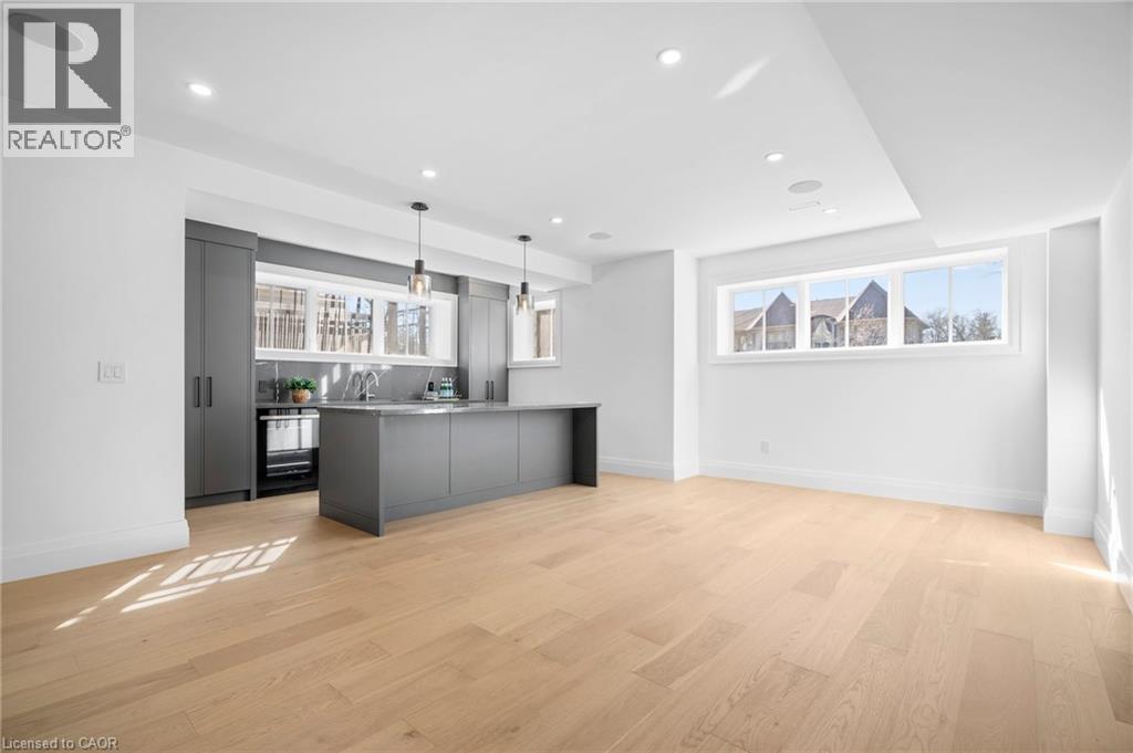 Kitchen with gray cabinetry, light countertops, hanging light fixtures, light wood-type flooring, and healthy amount of natural light - 1322 Minaki Road, Mississauga, ON - Indoor Photo Showing Kitchen