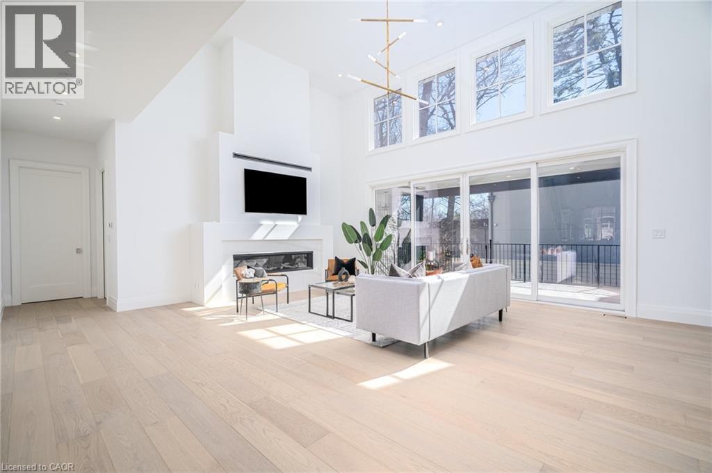 Living area with light wood-type flooring, a towering ceiling, a chandelier, a glass covered fireplace, and recessed lighting - 1322 Minaki Road, Mississauga, ON - Indoor With Fireplace