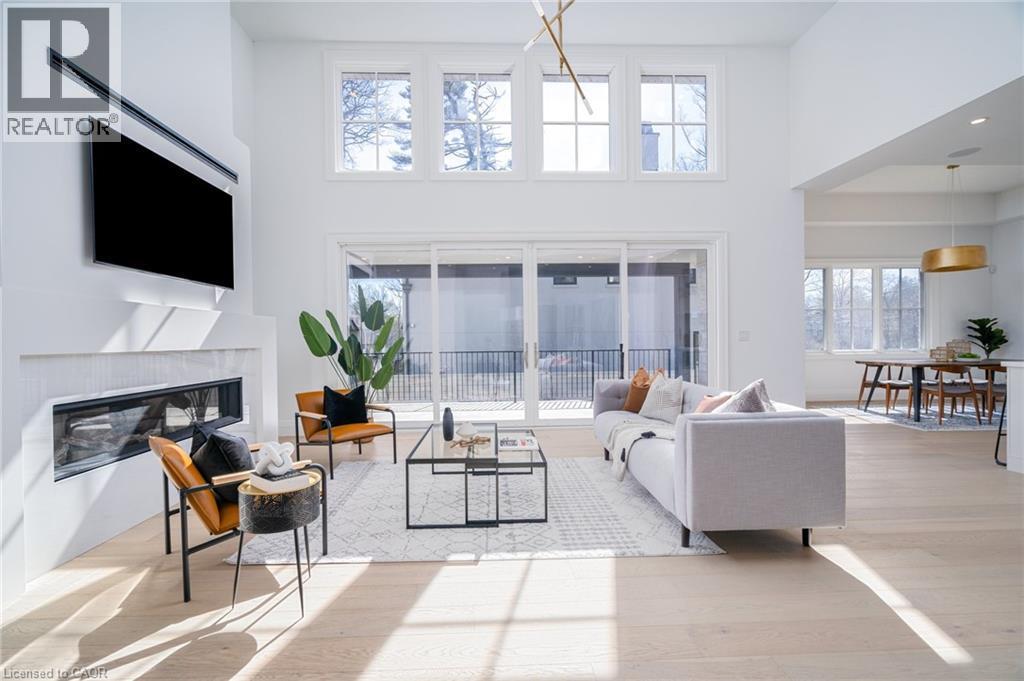 Living area featuring a towering ceiling, a premium fireplace, and light wood-type flooring - 1322 Minaki Road, Mississauga, ON - Indoor Photo Showing Living Room With Fireplace