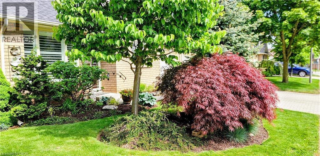 Manicured front yard with mature trees and diverse landscaping - 165 Main Street E Unit# 9, Grimsby, ON - Outdoor