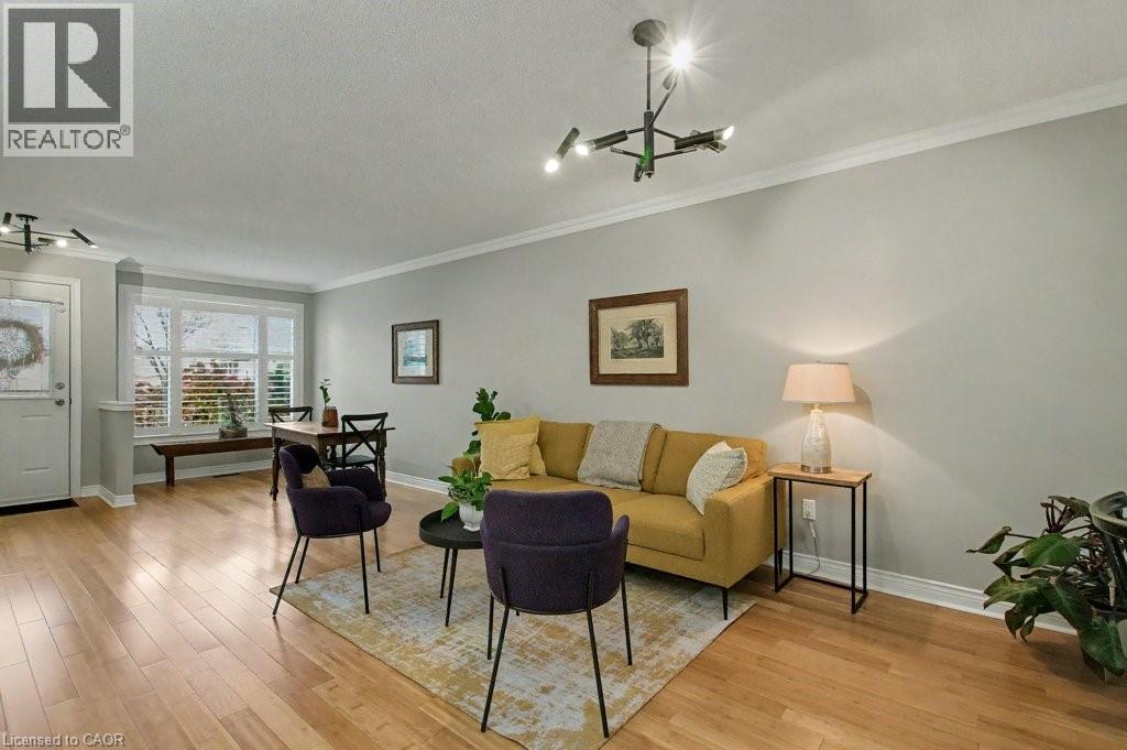 Living area featuring light wood-style floors, a chandelier, crown molding, and a textured ceiling - 165 Main Street E Unit# 9, Grimsby, ON - Indoor Photo Showing Living Room