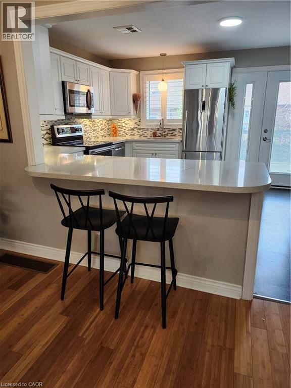 Kitchen with a peninsula, refrigerator, a kitchen bar, and stainless steel range - 165 Main Street E Unit# 9, Grimsby, ON - Indoor Photo Showing Kitchen