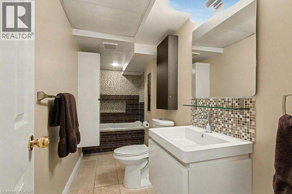 Full bath featuring vanity, tiled shower / bath, light tile patterned floors, and tasteful backsplash - 165 Main Street E Unit# 9, Grimsby, ON - Indoor Photo Showing Bathroom