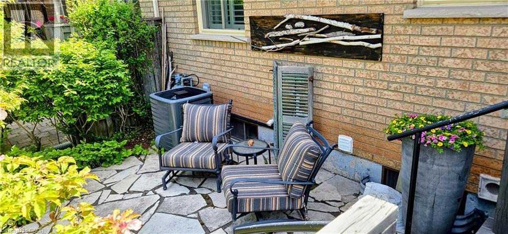 Flagstone patio with surrounding shrubbery and brick exterior - 165 Main Street E Unit# 9, Grimsby, ON - Outdoor With Exterior