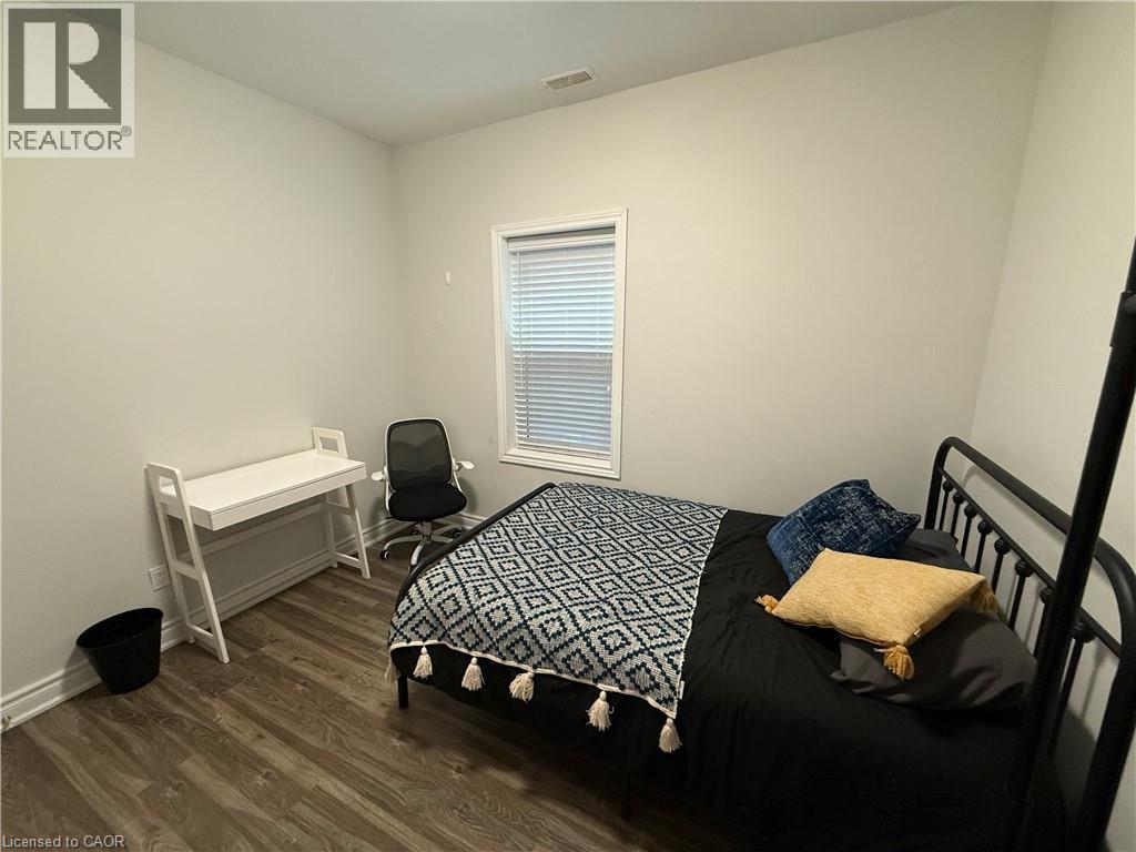 Bedroom with dark wood-style flooring and baseboards - 106 Spadina Avenue Unit# 1, Hamilton, ON - Indoor Photo Showing Bedroom
