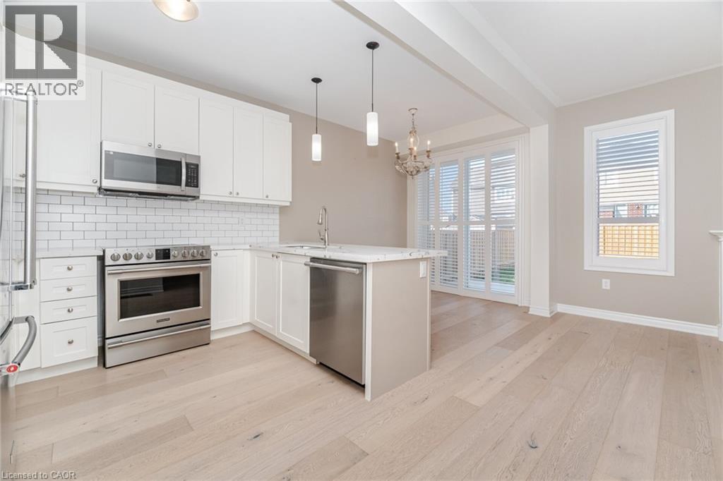 Kitchen with appliances with stainless steel finishes, tasteful backsplash, white cabinetry, a peninsula, and decorative light fixtures - 28 Pickett Place, Cambridge, ON - Indoor Photo Showing Kitchen With Stainless Steel Kitchen With Upgraded Kitchen