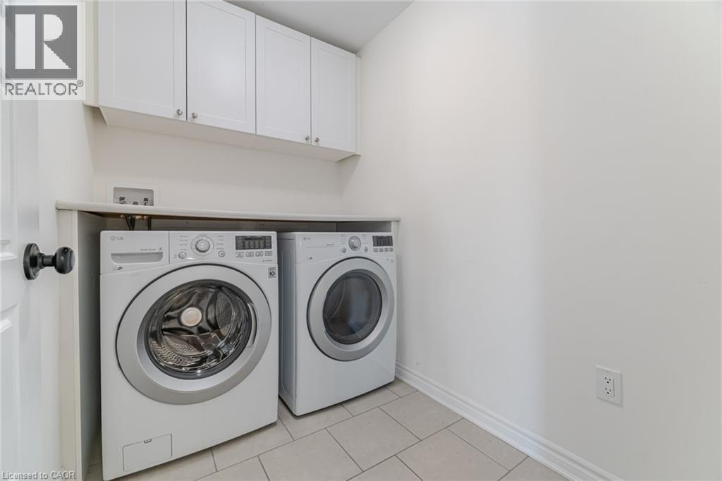Washroom with light tile patterned flooring, cabinet space, and washer and clothes dryer - 28 Pickett Place, Cambridge, ON - Indoor Photo Showing Laundry Room