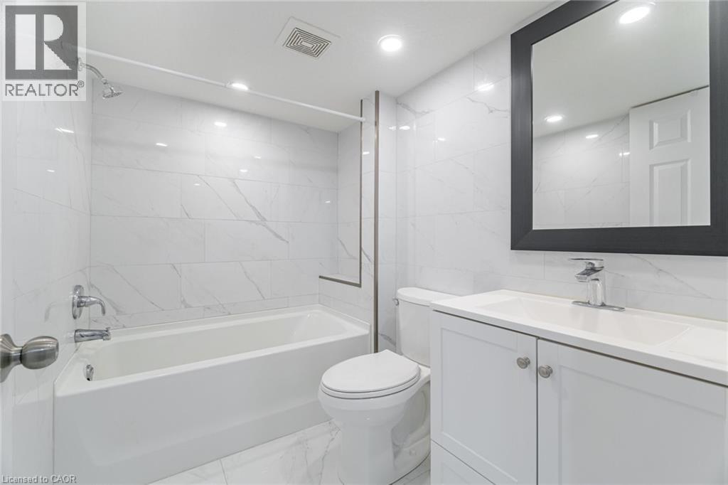 Full bathroom featuring tile walls, light marble finish flooring, washtub / shower combination, vanity, and recessed lighting - 28 Pickett Place, Cambridge, ON - Indoor Photo Showing Bathroom