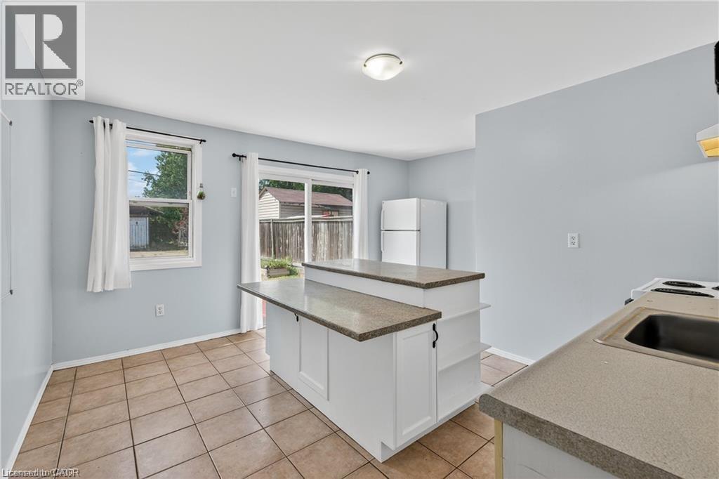 Kitchen with white cabinetry, freestanding refrigerator, a center island, and light tile patterned floors - 111 Hillyard Street, Hamilton, ON - Indoor