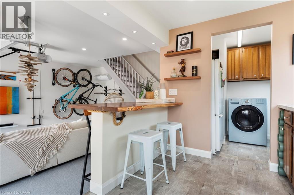 Kitchen featuring a breakfast bar area, washer / dryer, a peninsula, open shelves, and freestanding refrigerator - 197 Cedar Drive, Turkey Point, ON - Indoor Photo Showing Laundry Room