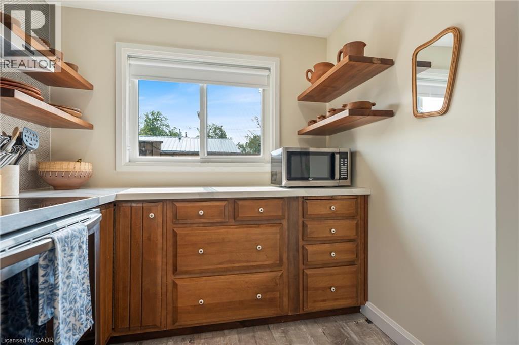 Kitchen with open shelves, light countertops, stainless steel appliances, brown cabinetry, and dark wood-style flooring - 197 Cedar Drive, Turkey Point, ON - Indoor Photo Showing Kitchen