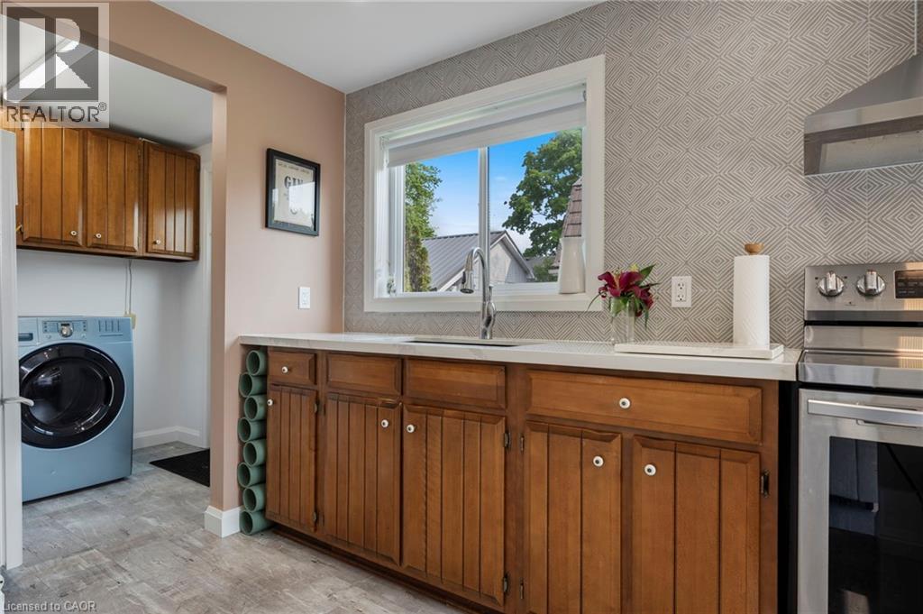 Laundry area with washer / clothes dryer, cabinet space, and wallpapered walls - 197 Cedar Drive, Turkey Point, ON - Indoor Photo Showing Laundry Room