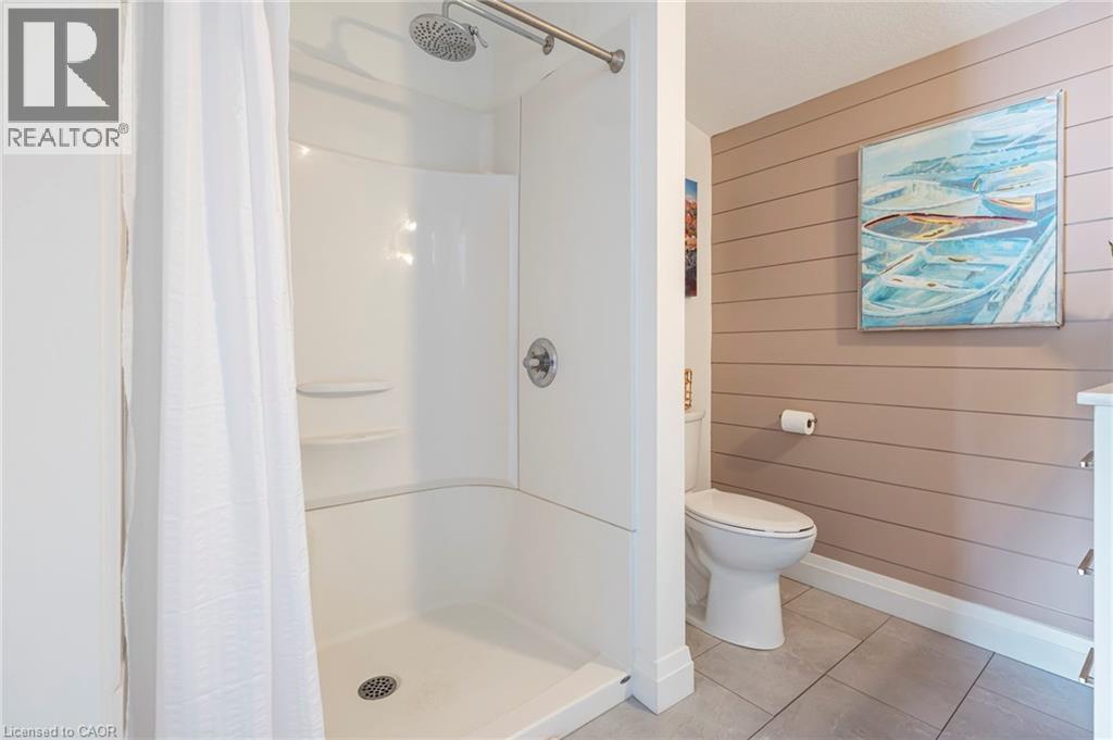 Full bath with wood walls, a shower stall, tile patterned flooring, and vanity - 197 Cedar Drive, Turkey Point, ON - Indoor Photo Showing Bathroom