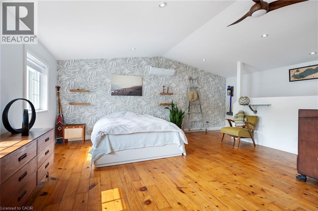 Bedroom with an accent wall, wallpapered walls, light wood-style flooring, a ceiling fan, and vaulted ceiling - 197 Cedar Drive, Turkey Point, ON - Indoor Photo Showing Bedroom