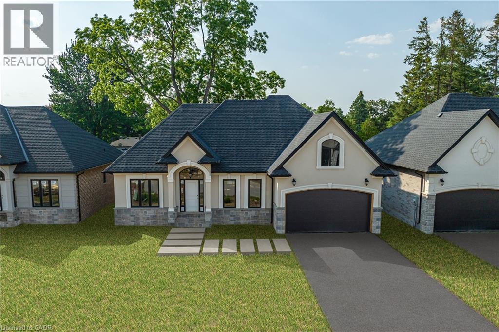 French country style house with stucco siding, stone siding, driveway, a front lawn, and a garage - 57 Cesar Place, Ancaster, ON - Outdoor With Facade